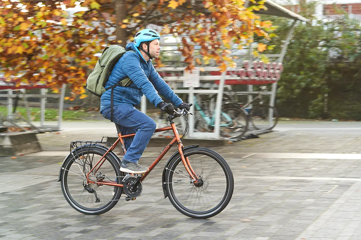 Male cyclist in a blue coat riding the Ridgeback Expedition commuter bike
