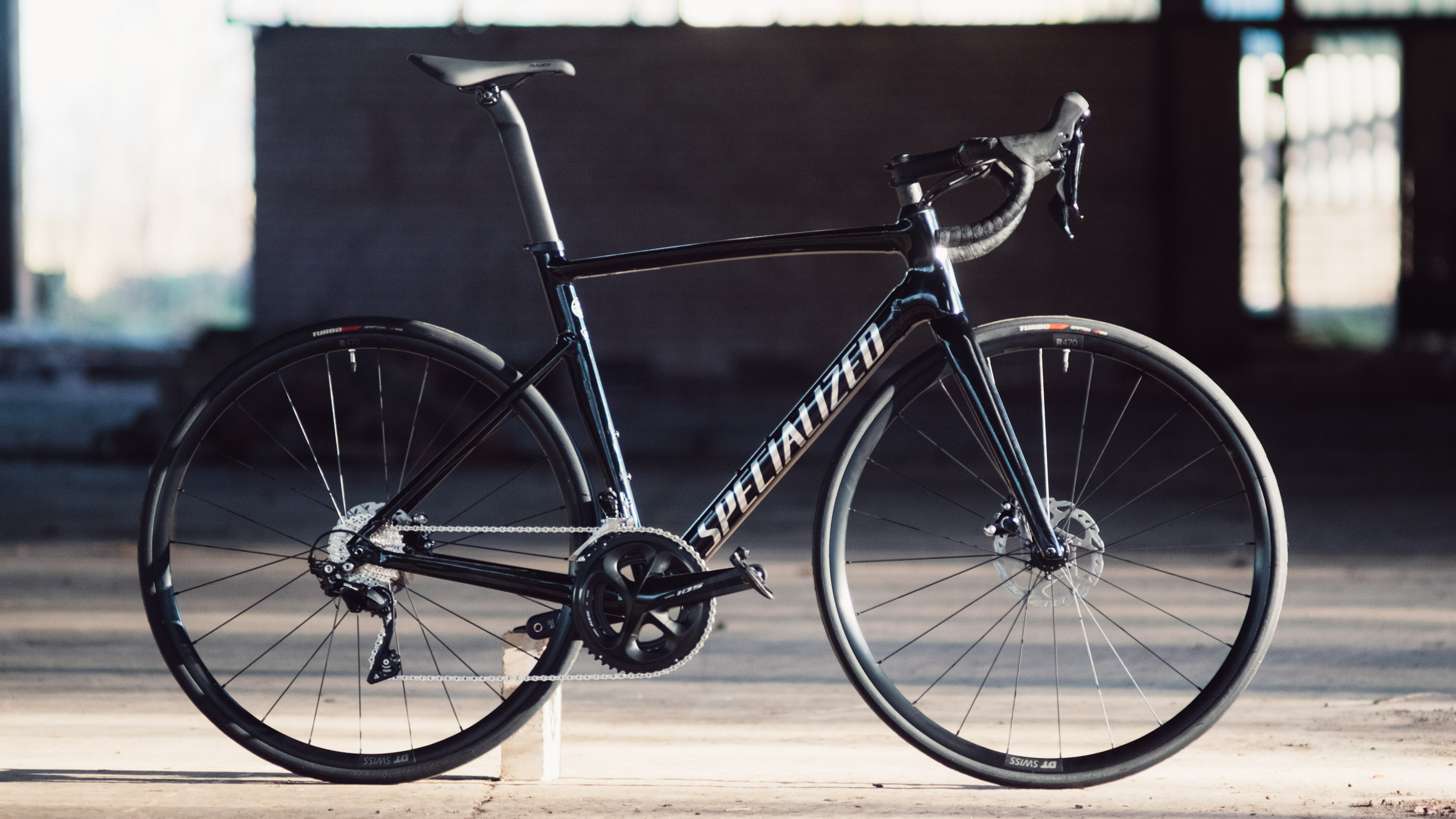 A black bike stands side on in an abandoned warehouse