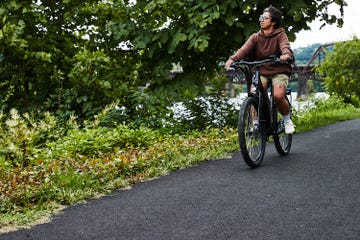 A person riding a bicycle along a paved path surrounded by greenery