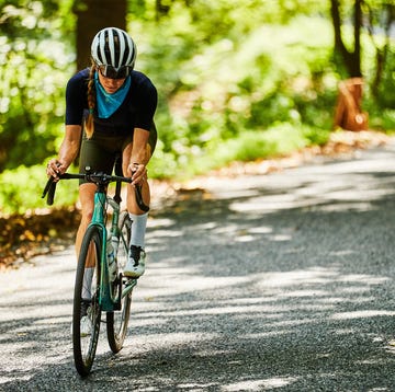 A cyclist looking down at their cycling computer while riding up a hill. a cyclist looking down at their cycling computer while riding up a hill