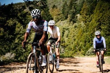 Cyclists riding on a dirt path surrounded by trees