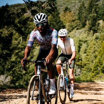 Cyclists riding on a dirt path surrounded by trees Cyclists riding on a dirt path surrounded by trees