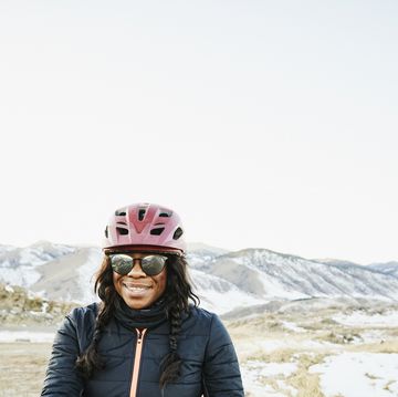 portrait of smiling female cyclist riding gravel bike at sunset on winter evening