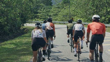 rear view asian chinese cyclist leader leading team cycling in rural area during weekend morning