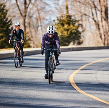 two people riding bikes on a road two people riding bikes on a road