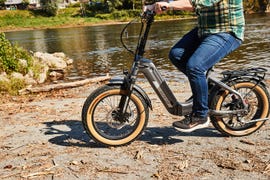 person riding an electric bike near a river