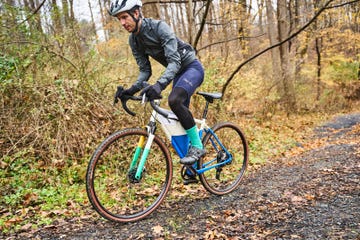 a cyclist riding on a gravel path surrounded by autumn foliage