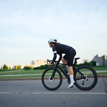 young woman training on road bicycle at city street